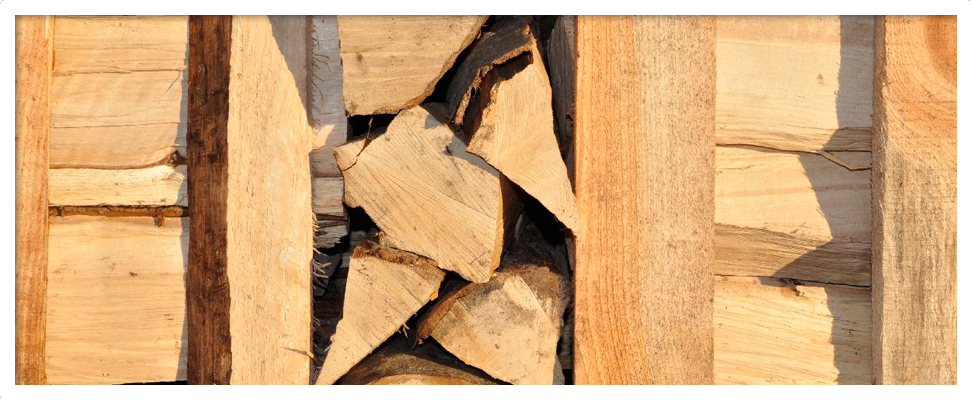 Ofenfertig gespaltenes Holz hinter Holzlatten gestapelt